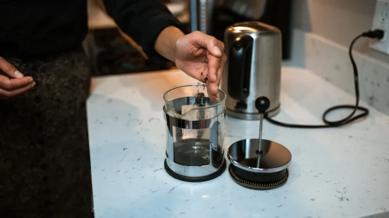 Someone brewing coffee in a French press on a kitchen counter