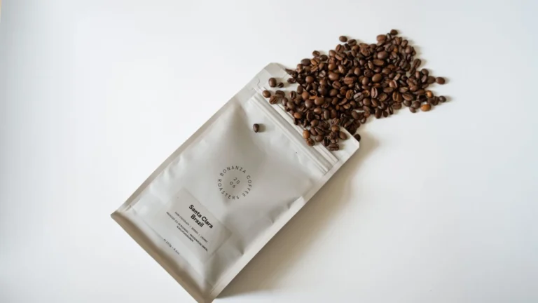 Bag of freshly roasted coffee beans spilling onto a white surface