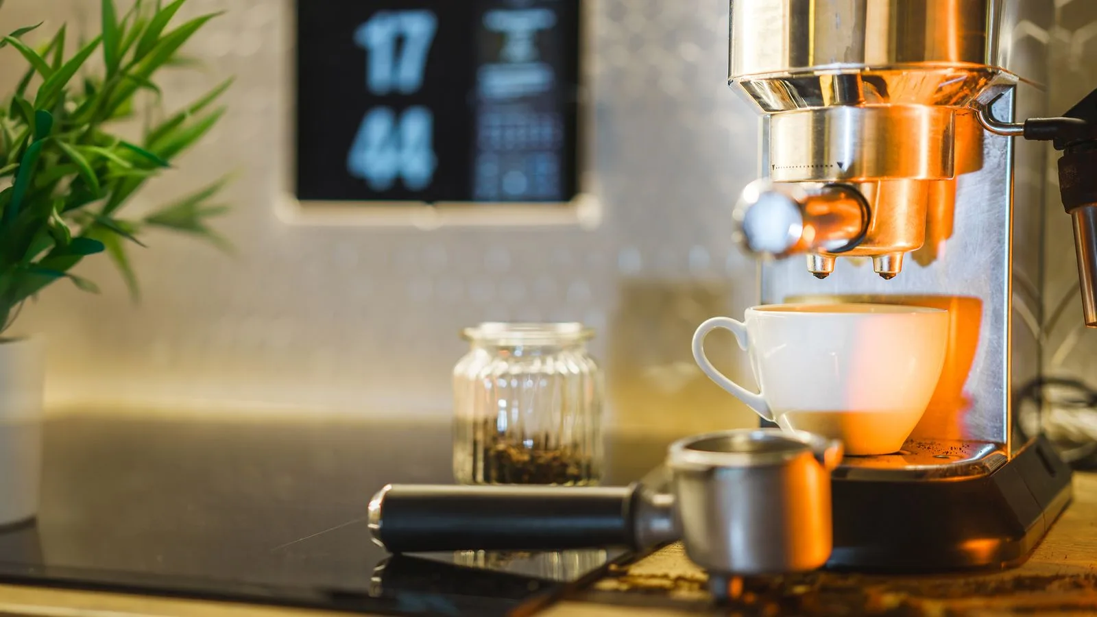 Home espresso machine pulling a shot beside a portafilter on a kitchen counter
