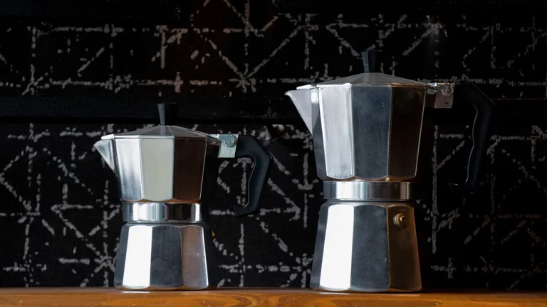 Two stovetop moka pots of different sizes on a wooden shelf