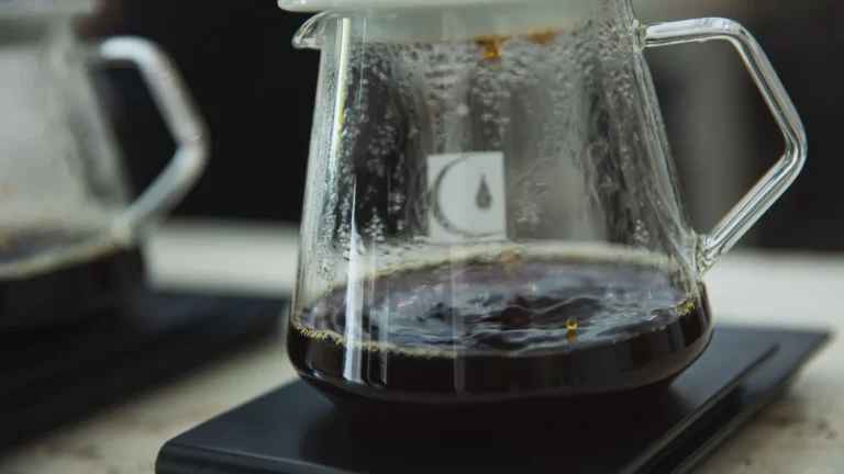 Brewed coffee dripping through a filter into a glass server on a scale